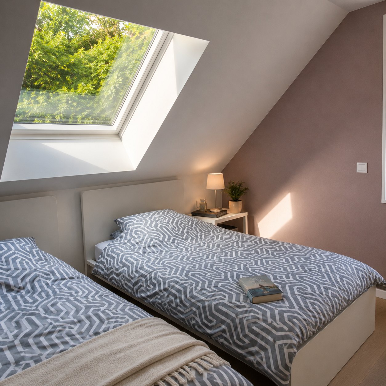 Seconde chambre sous les combles avec deux lits simples et un velux ouvert sur les arbres