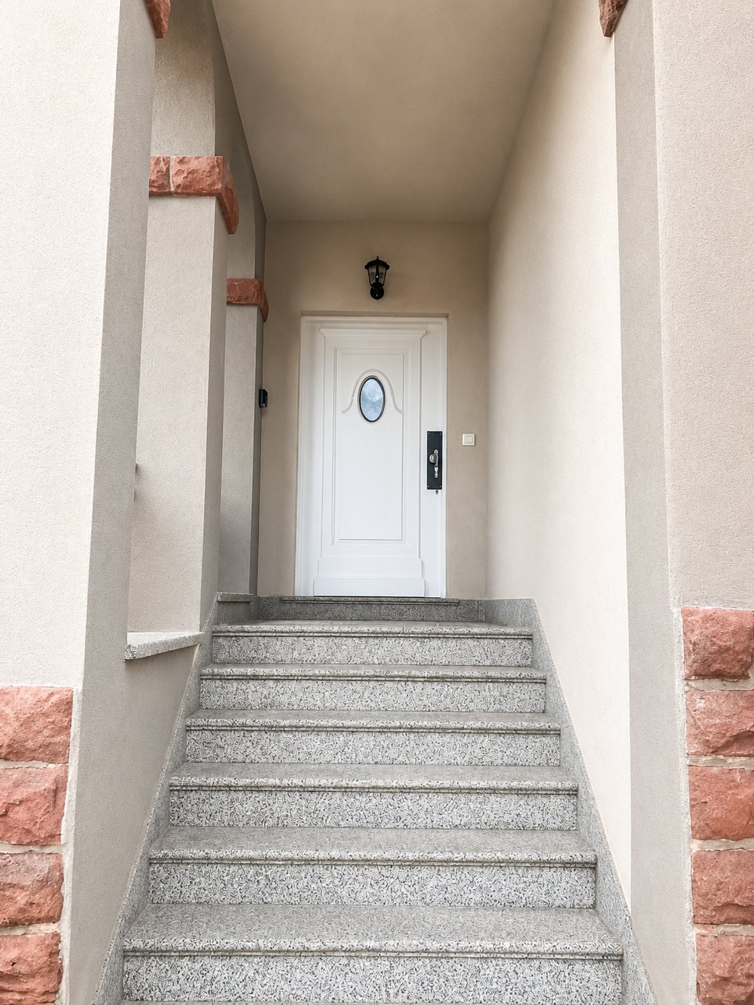 Escalier extérieur de granit menant à la porte d'entrée blanche privative de l'appartement