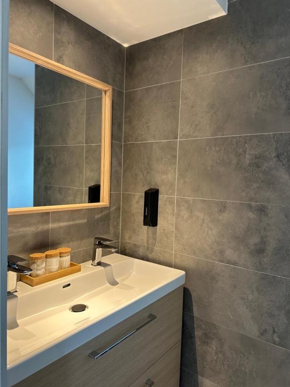 Salle de bains carrelée gris anthracite, large vasque, grand miroir à cadre bois
