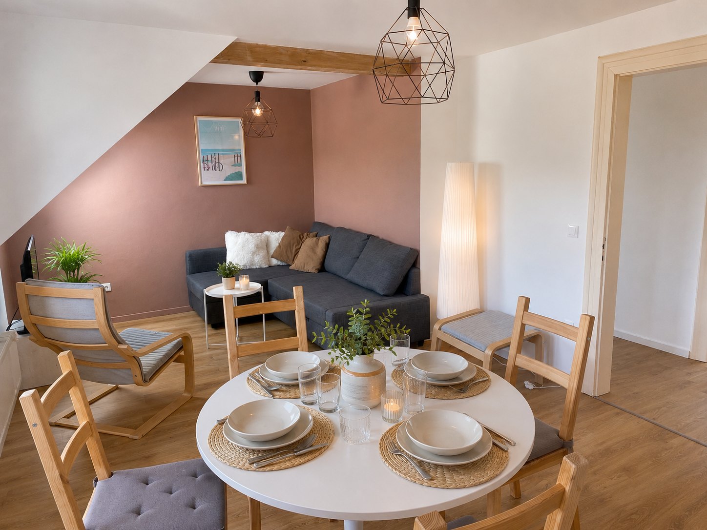 Salon avec canapé-lit d'angle gris devant un mur terracotta, dans le prolongement du coin repas